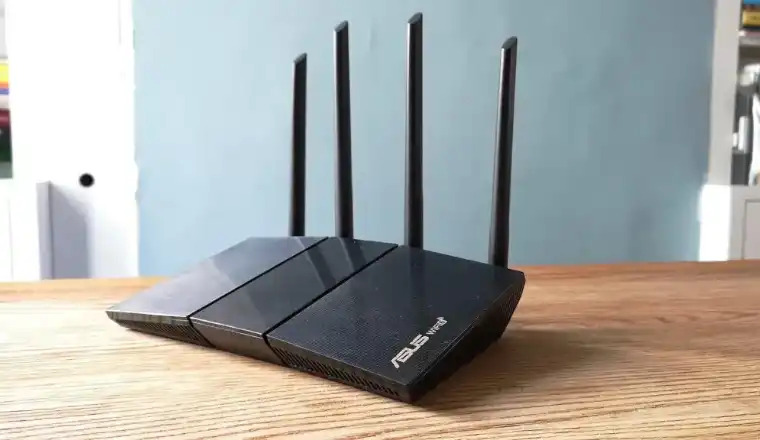 ASUS RT-AX55 router with four antennas on wooden table.