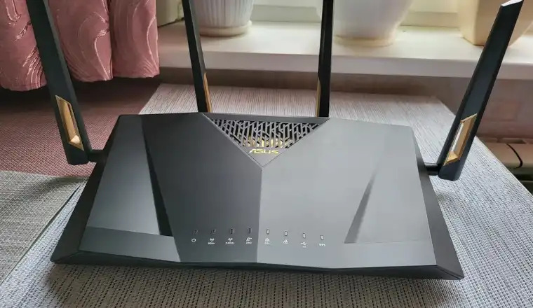 ASUS RT-AX88U PRO AX6000 router with four antennas placed on fabric surface.