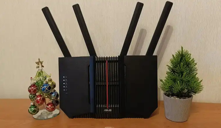 ASUS RT-BE92U BE9700 router with four antennas between decorations and a plant.