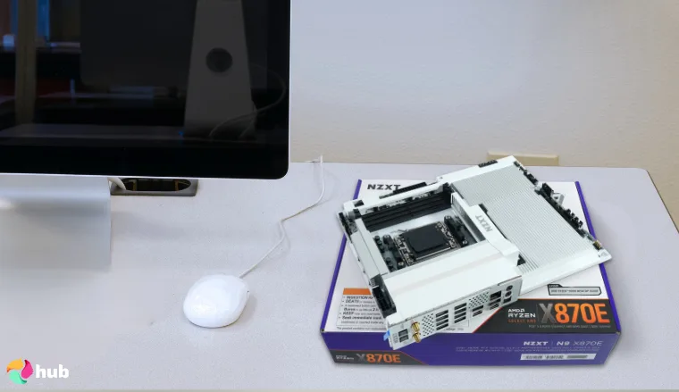 NZXT N9 X870E Motherboard on a white office desk with professional arrangement for a review