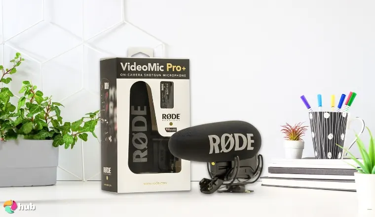 RØDE VideoMic Pro+ USB Microphone on a white office desk with decorative items for a review
