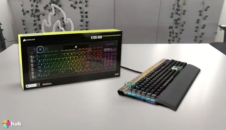 Corsair K100 RGB Optical-Mechanical Keyboard on a white office desk with natural light ready for a review