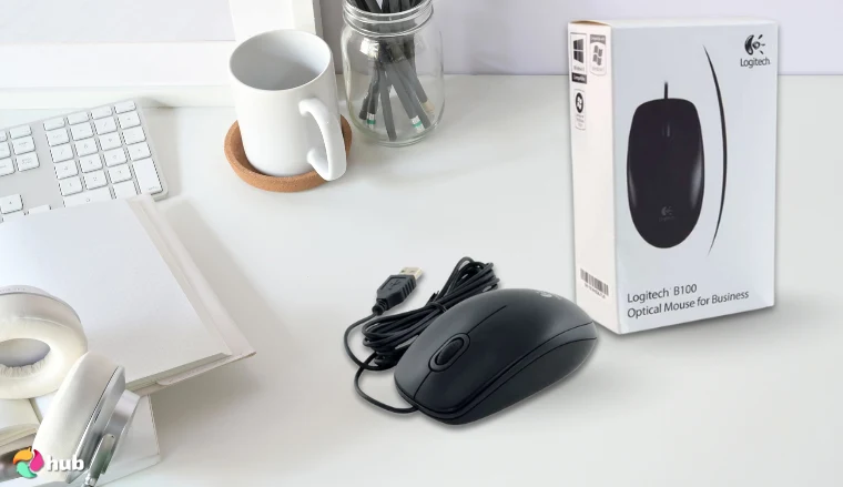 Logitech B100 Mouse on a white office desk with soft lighting for a review