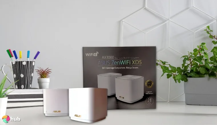 ASUS ZenWiFi AX Mini (XD5) Router on a white office desk with an editorial style for a review