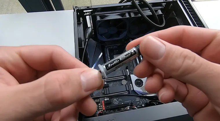 Tube of thermal paste in the foreground with a CPU motherboard in the background