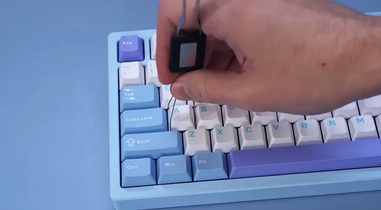 A hand pulling a mechanical switch out of a keyboard