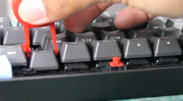 Keycap puller removing a switch from the keyboard plate