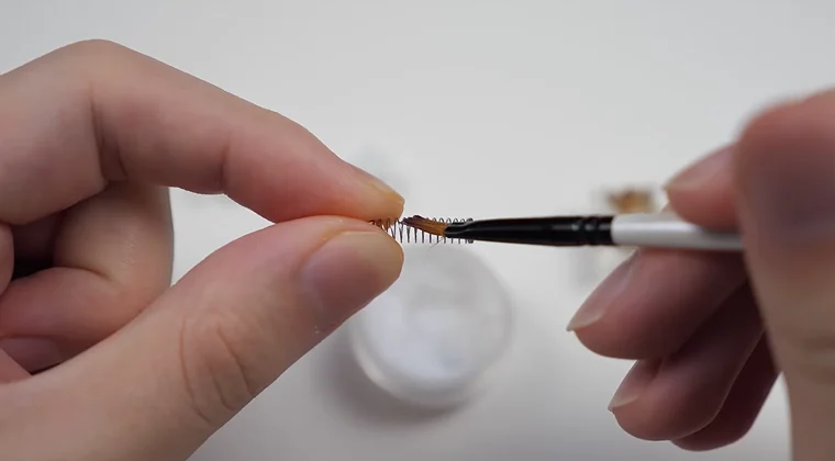 Close-up of a mechanical switch spring being lubricated with a fine brush