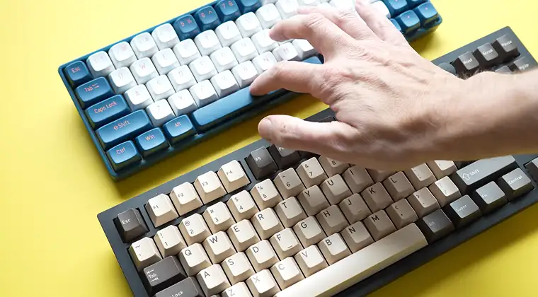 Two keyboards with a hand resting on one of them