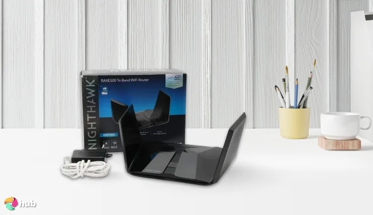 NETGEAR Nighthawk RAXE500 Wi-Fi Router on a white office desk with decorative items for a review