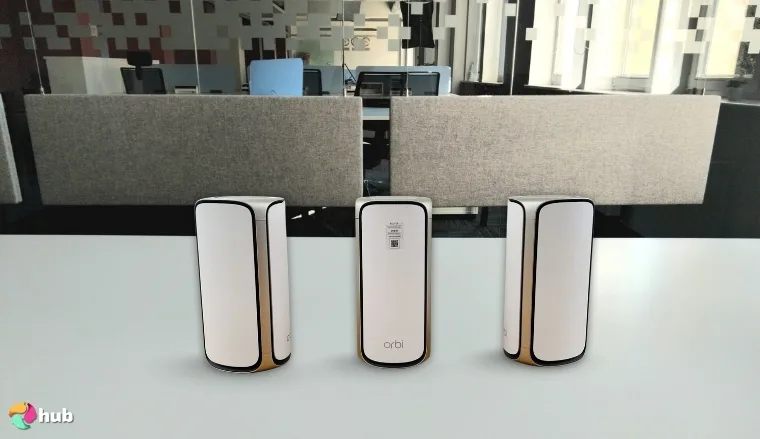 Netgear Orbi 970 Series Mesh Wi-Fi System on a white office desk with natural shadows for a review
