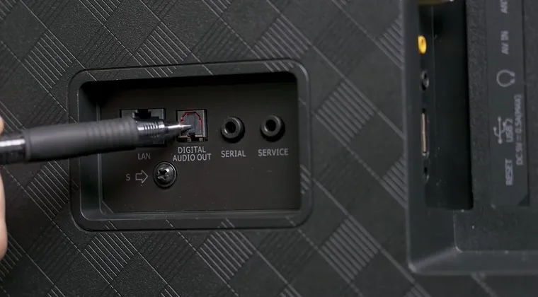 Back of a TV with an optical cable being plugged into the optical audio port