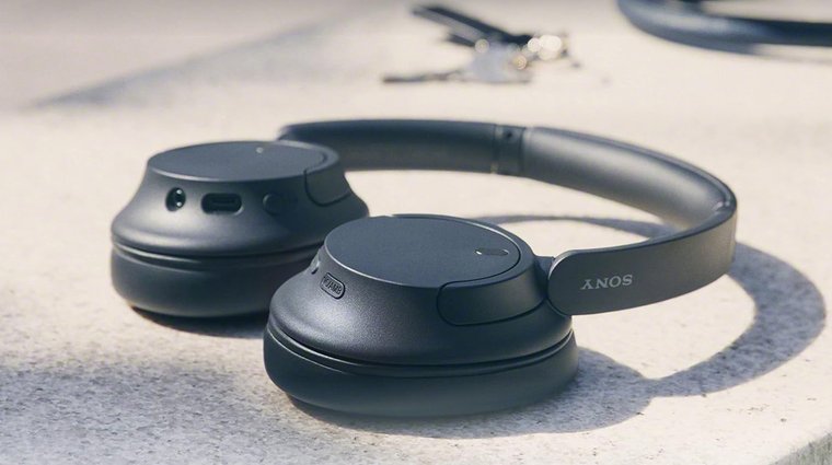 Sony WH CH720N wireless headphones on the pavement, sunlight shinning on it.