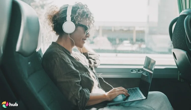 Woman working on a laptop on a bus, wearing headphones