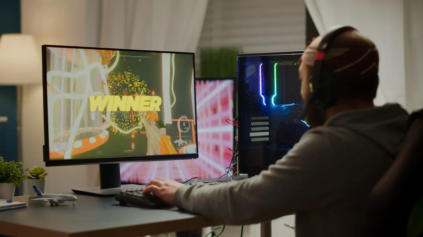 QA tester at desk with game running on screen