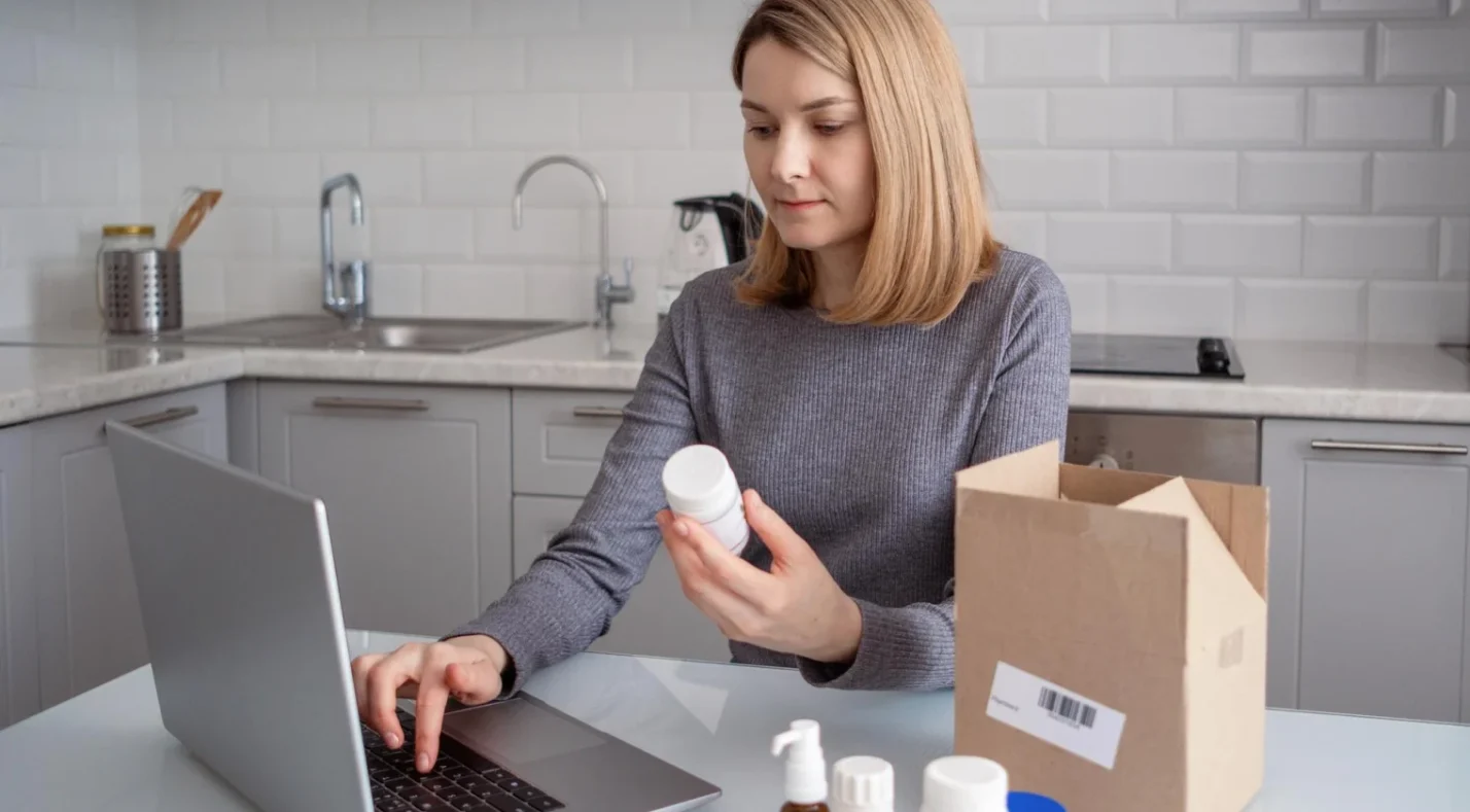 Woman holding a product jar while watching a laptop screen