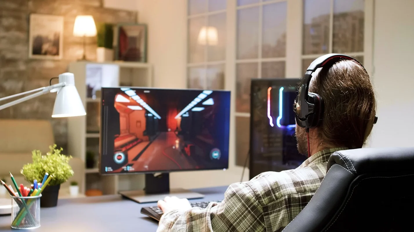 Player sitting in front of dual screen monitors
