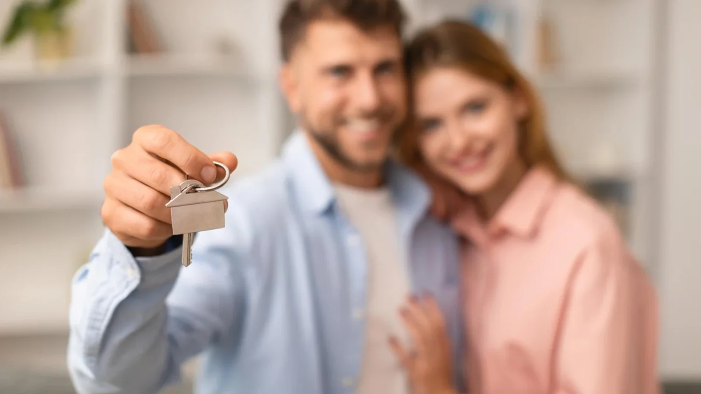 A couple standing and a man holds a key