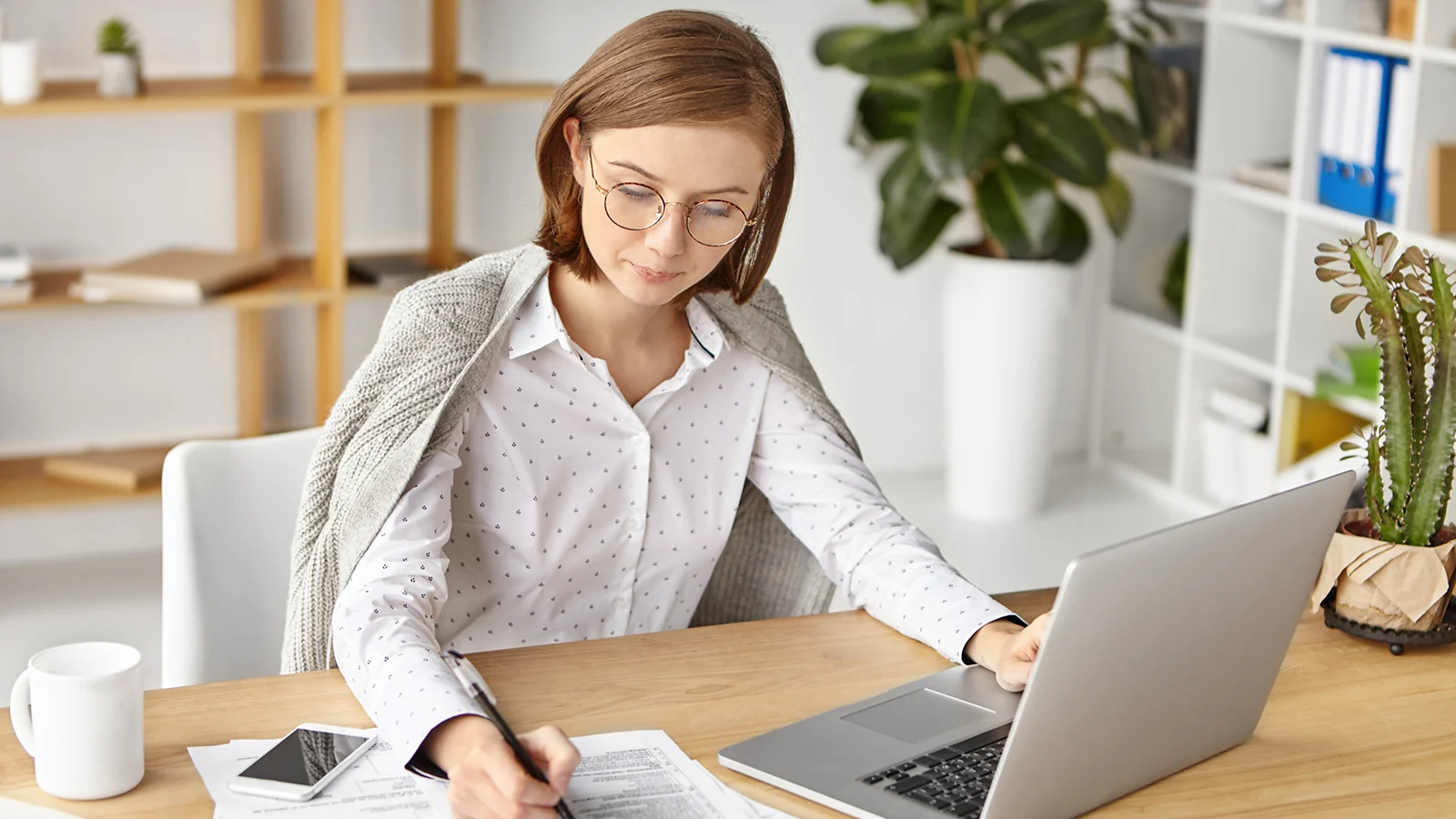 A woman sitting at the laptop and writting notes