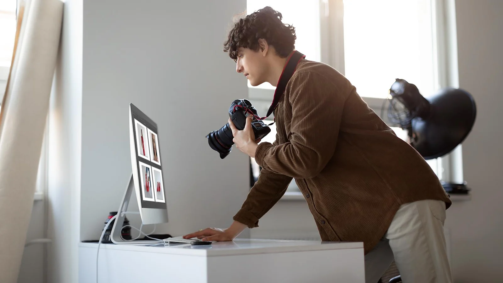 A man standing with a camera in his hands next to the desktop