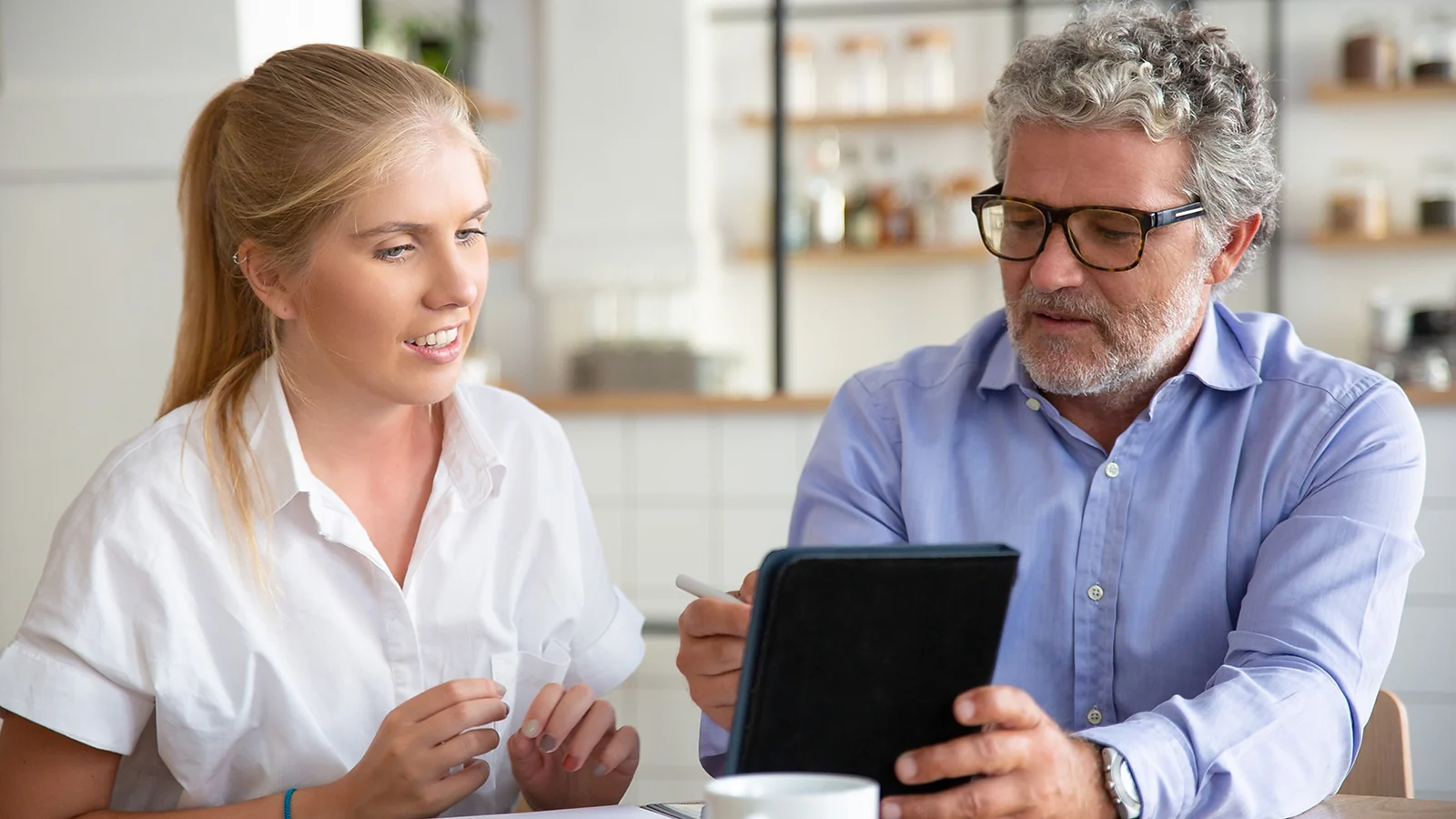 A man showing something on a tablet to a woman