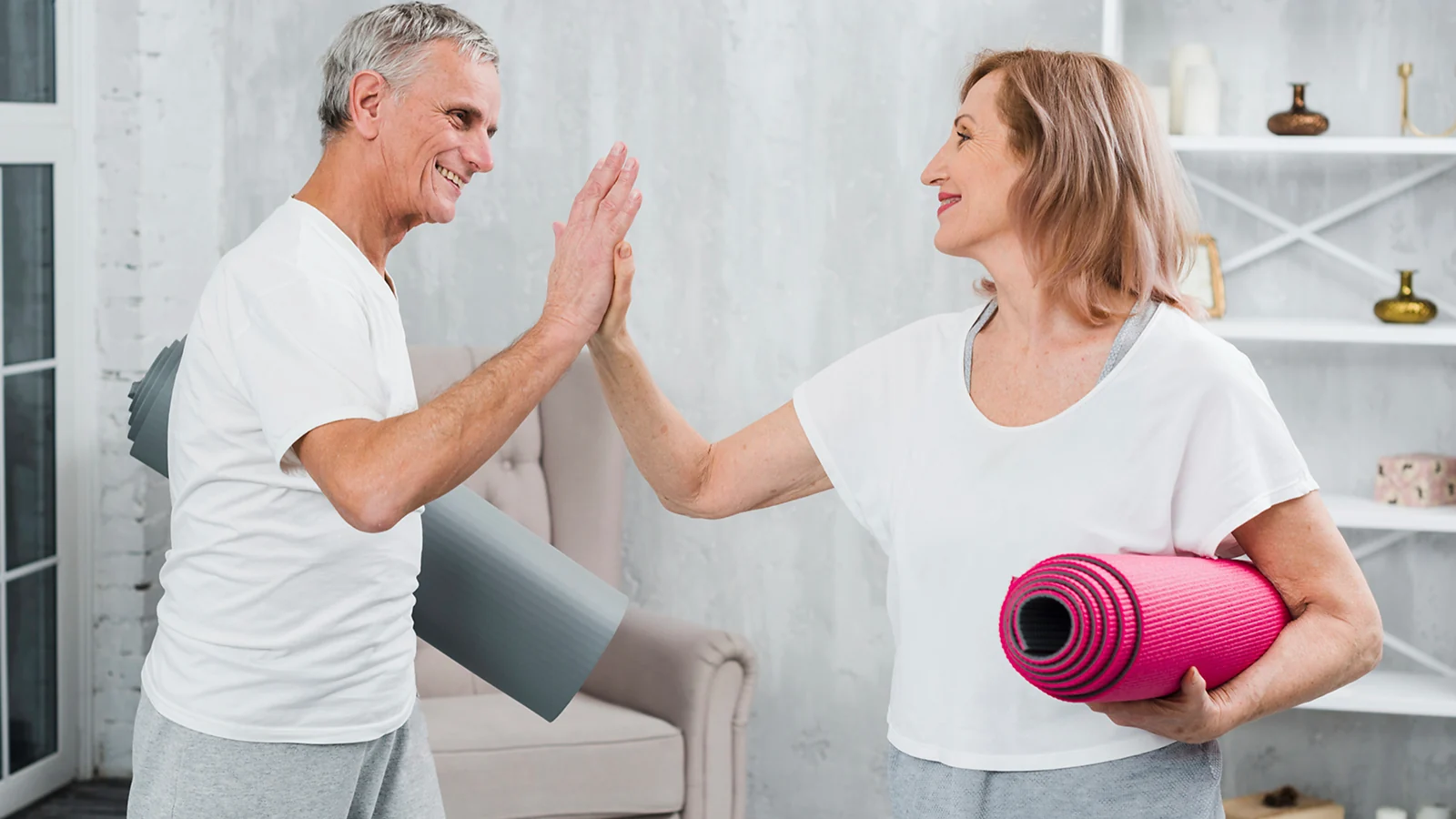 A man and a woman smiling at each other holding yoga mats