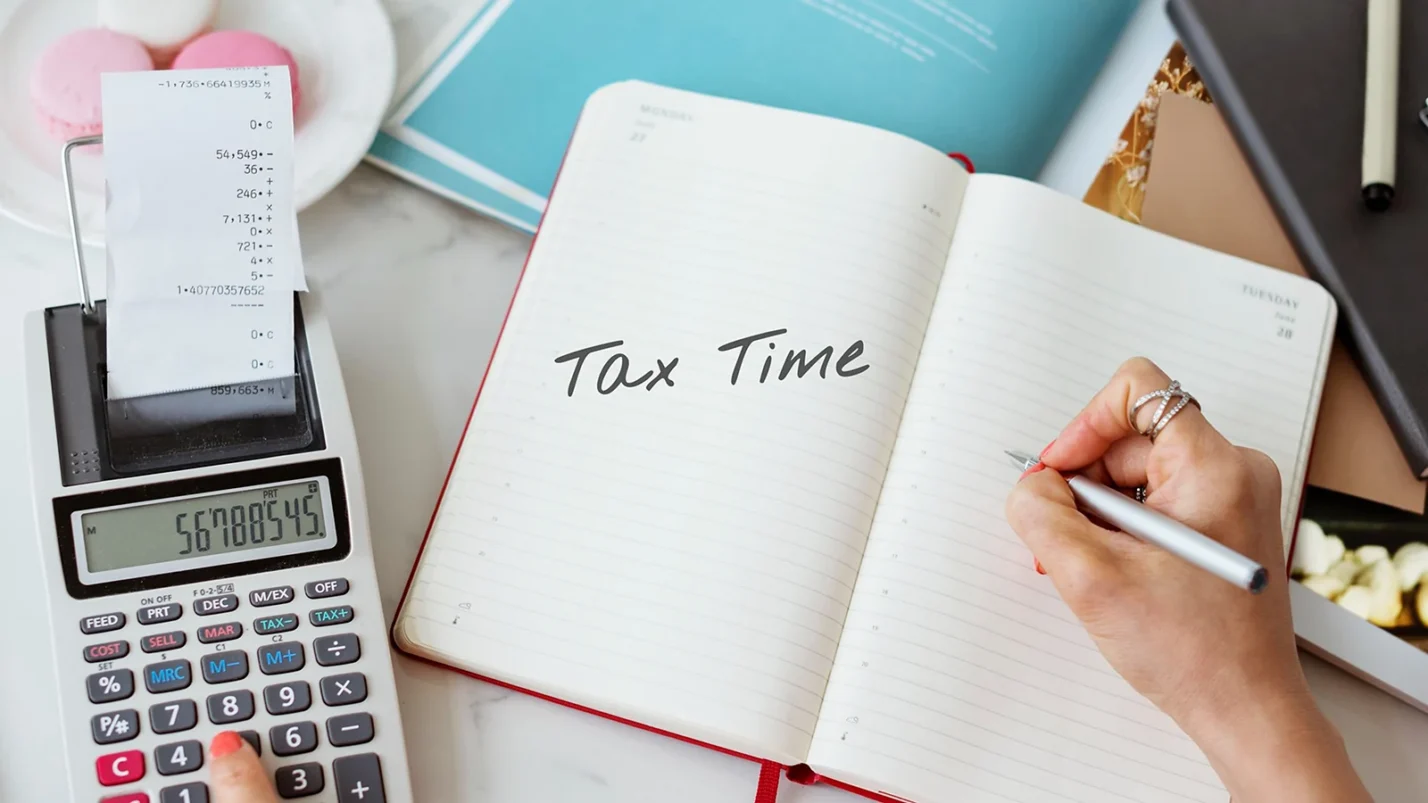A calculator and notes with the words "Tax Time" written on them