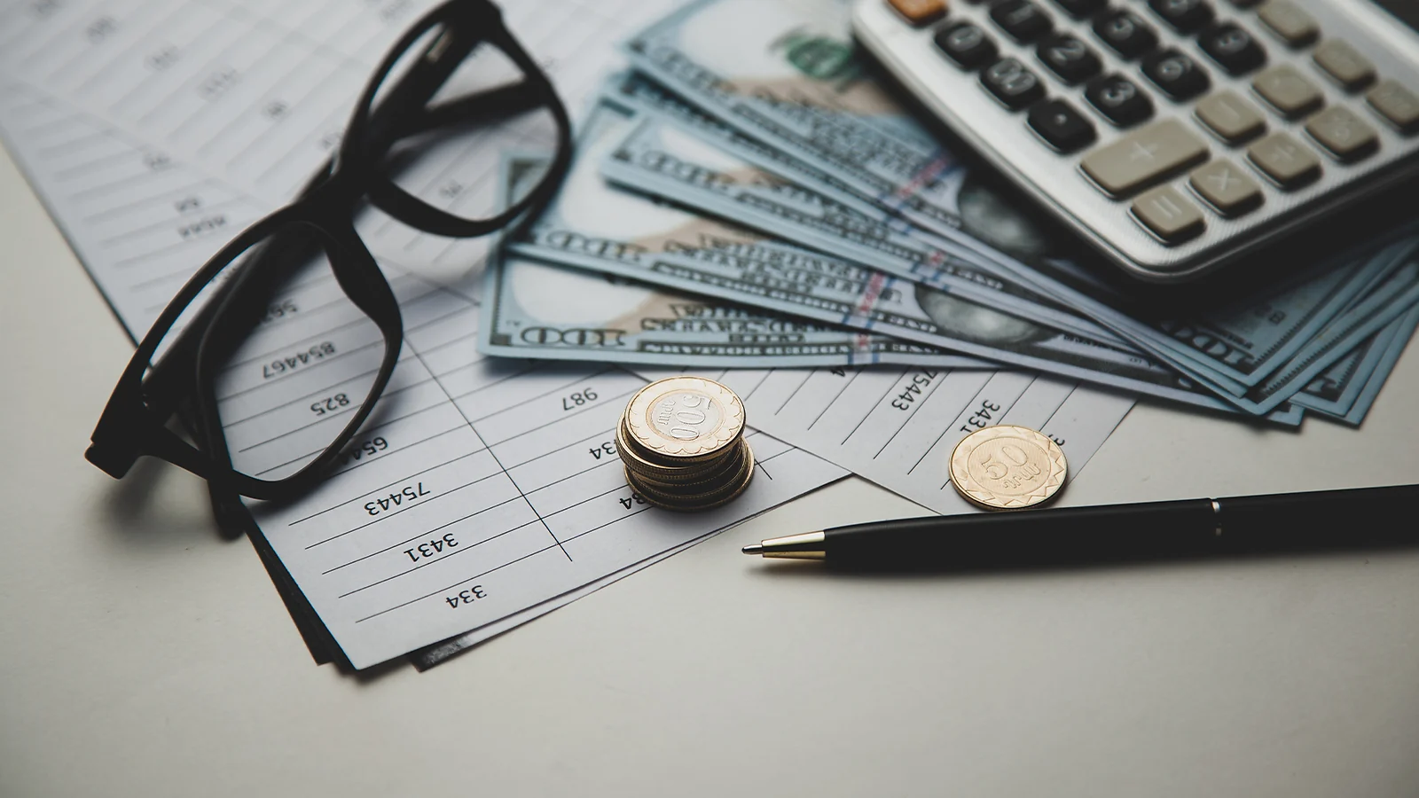 Counting Earnings: Hundred dollar bills, coins, and a calculator on a financial ledger