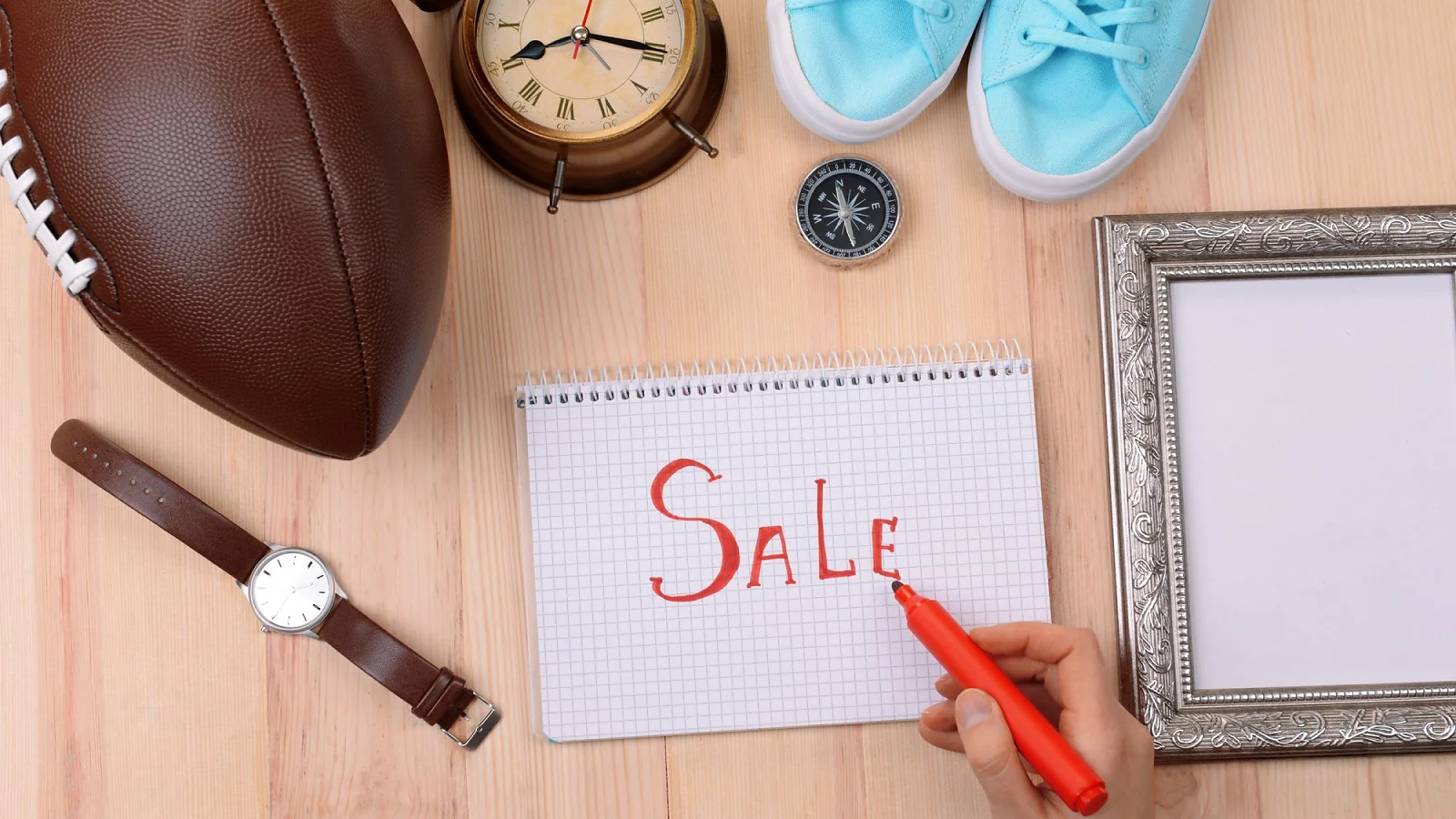 A composition of various items arranged around a note with the word "SALE"