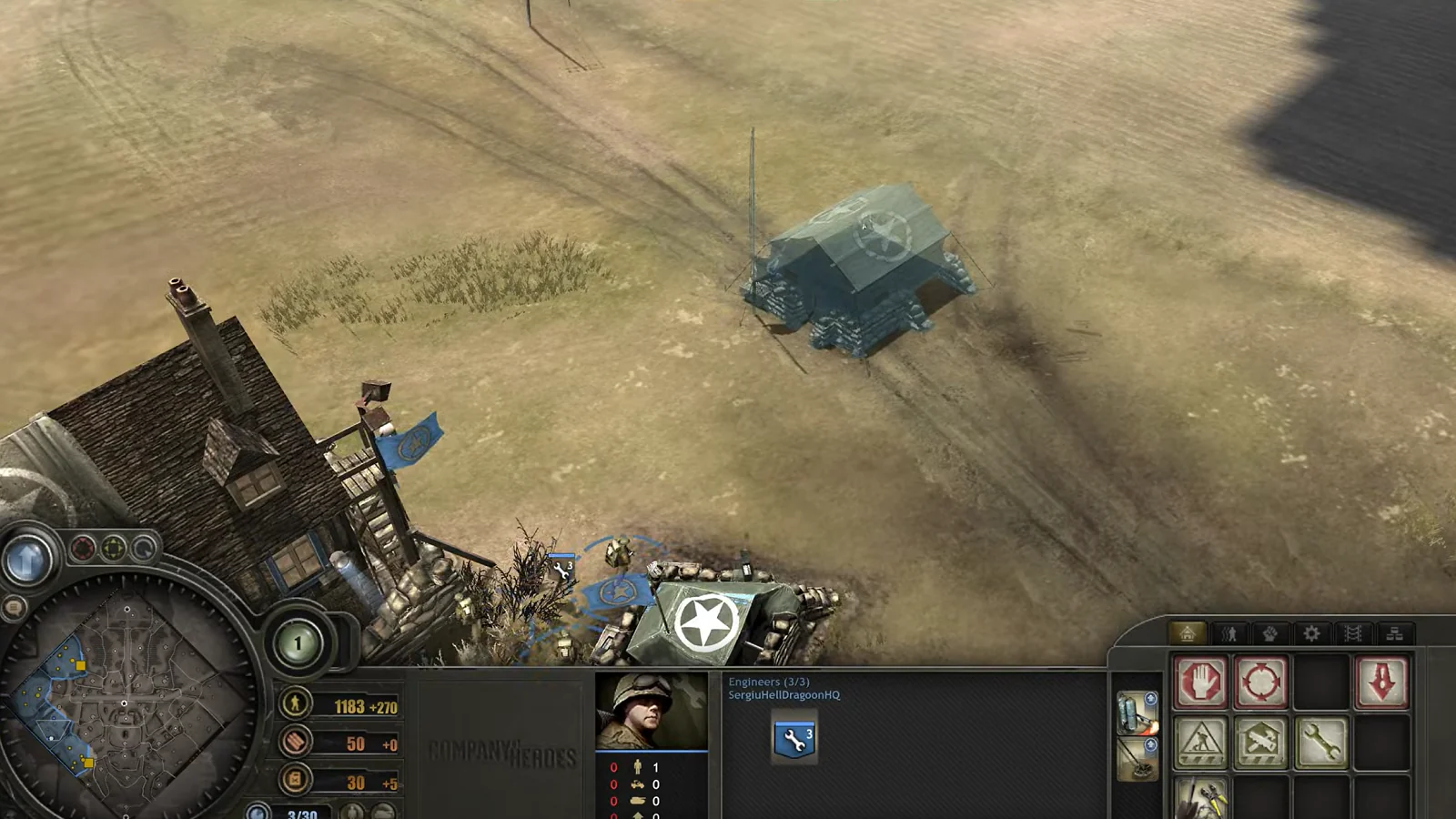 Overhead strategy view of military units and buildings on a dusty battlefield
