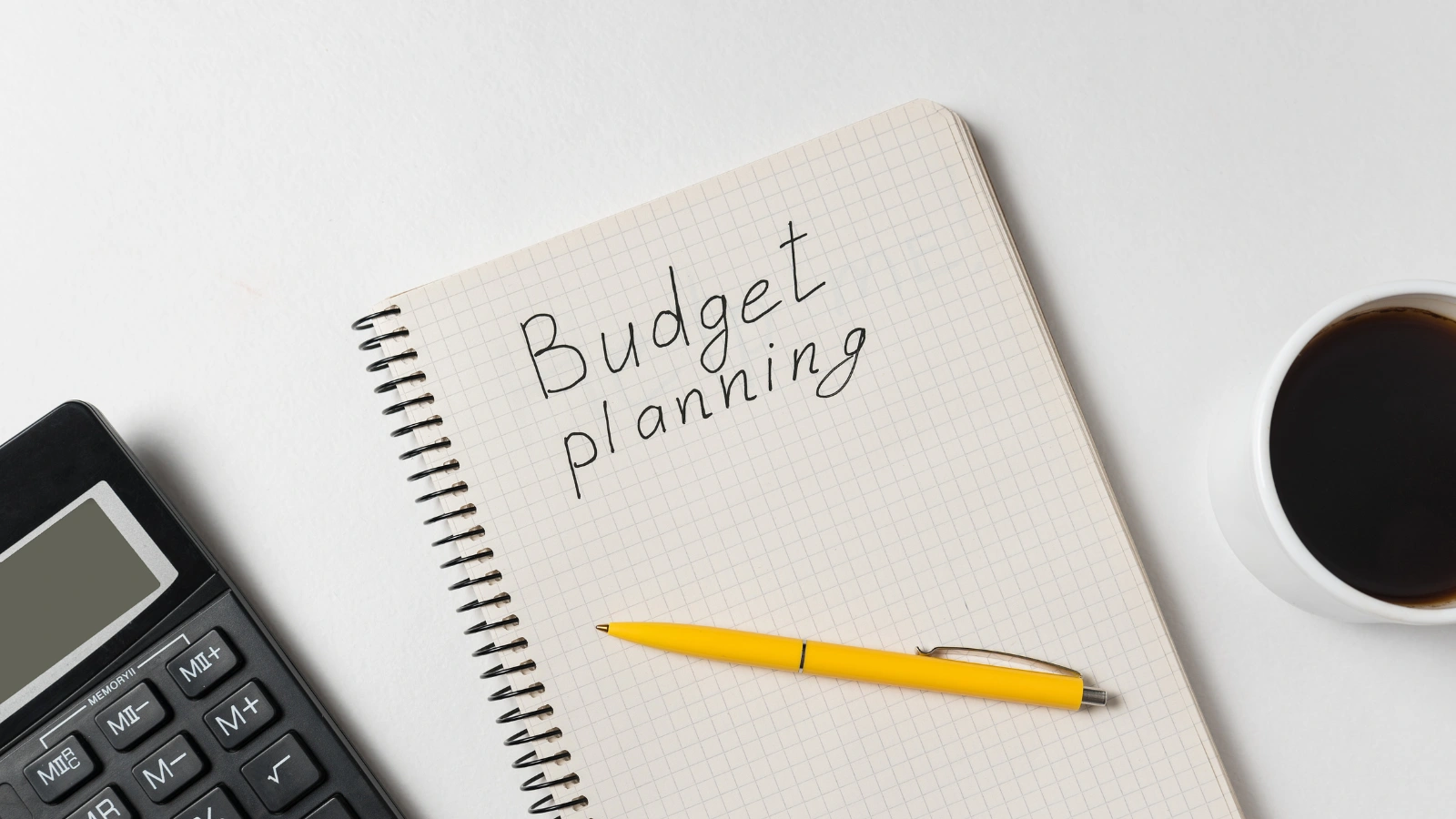 A notebook page totaling up startup costs next to a small stack of cash