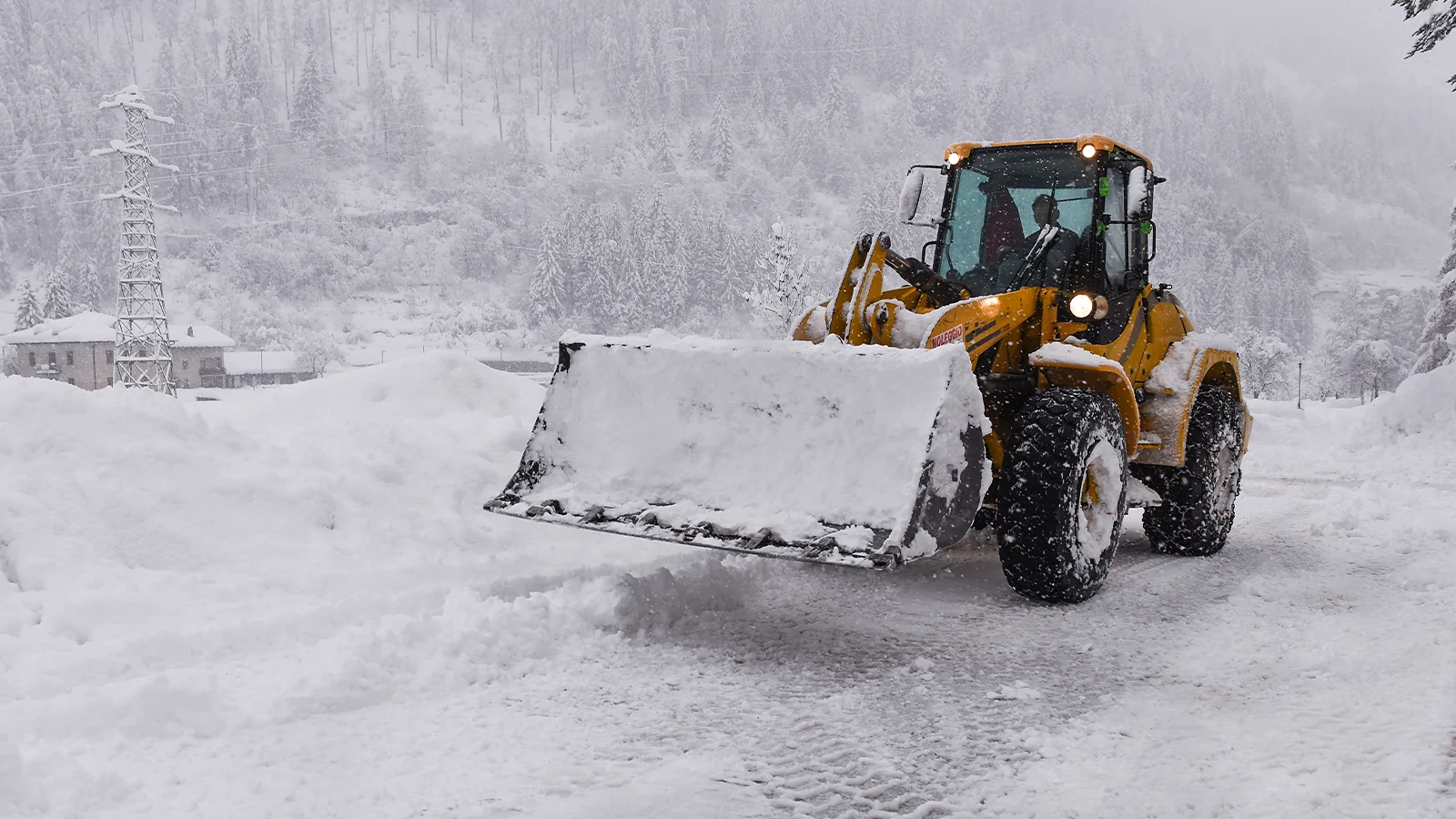 Winter side hustles - yellow loader clearing deep snow on a rural road
