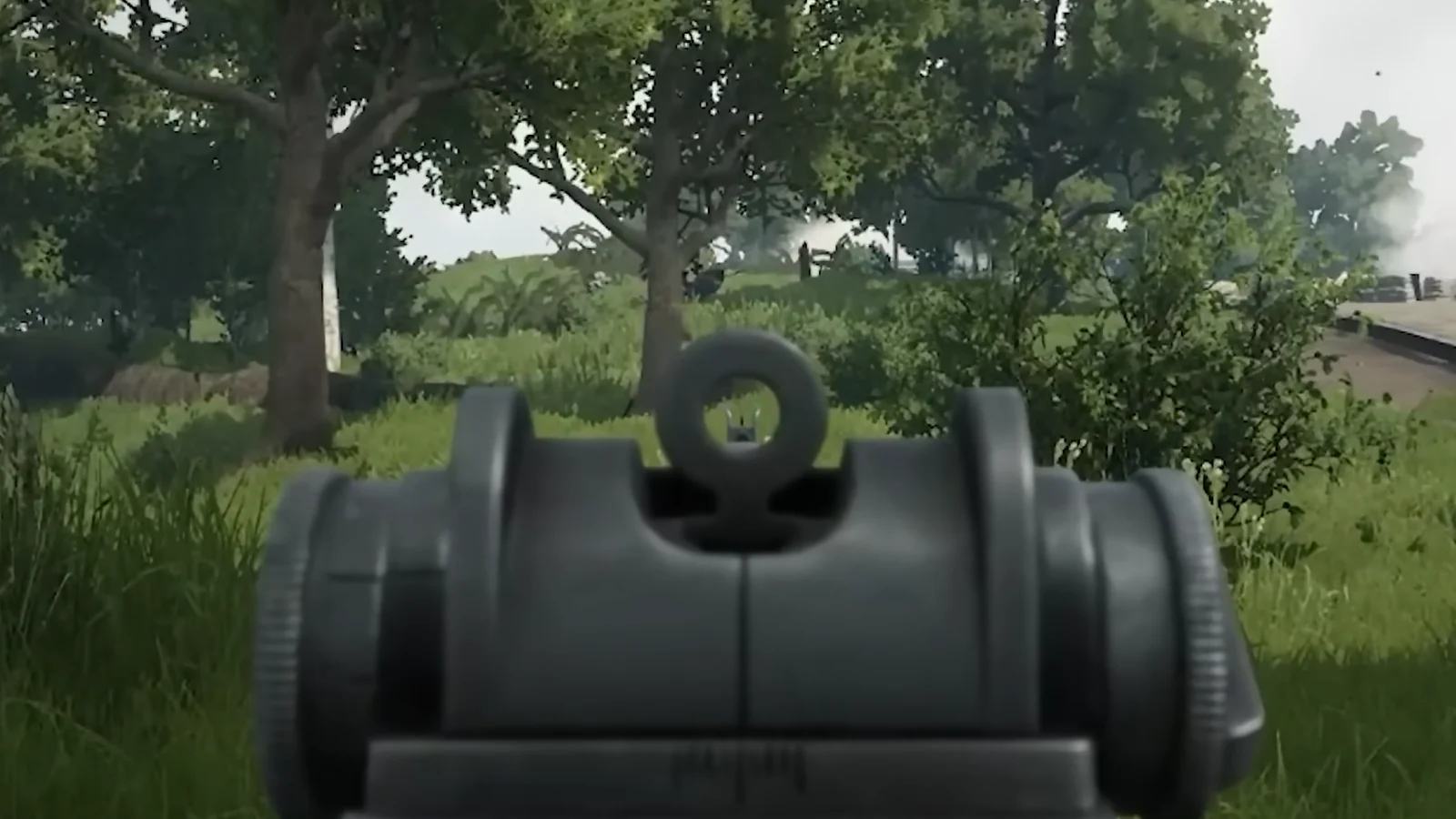 First-person view of a soldier aiming down a rifle sight in a wooded area.