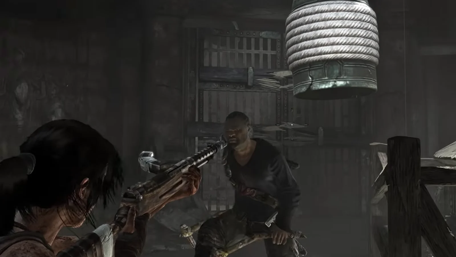 Tomb Raider gameplay showing Lara Croft aiming a rifle at an enemy inside a dark wooden building.
