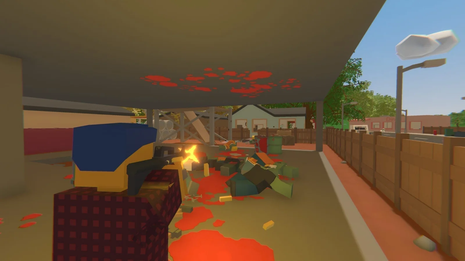 Unturned - O melhor jogo tipo DayZ para sobrevivência contra zombies, gratuito - Uma perspetiva na terceira pessoa de uma personagem em blocos, com gráficos low-poly, vestida com uma camisa xadrez e um capacete azul e amarelo, a disparar uma arma de fogo contra uma multidão de zombies em blocos, no meio de poças de sangue, debaixo de uma estrutura coberta numa zona suburbana
