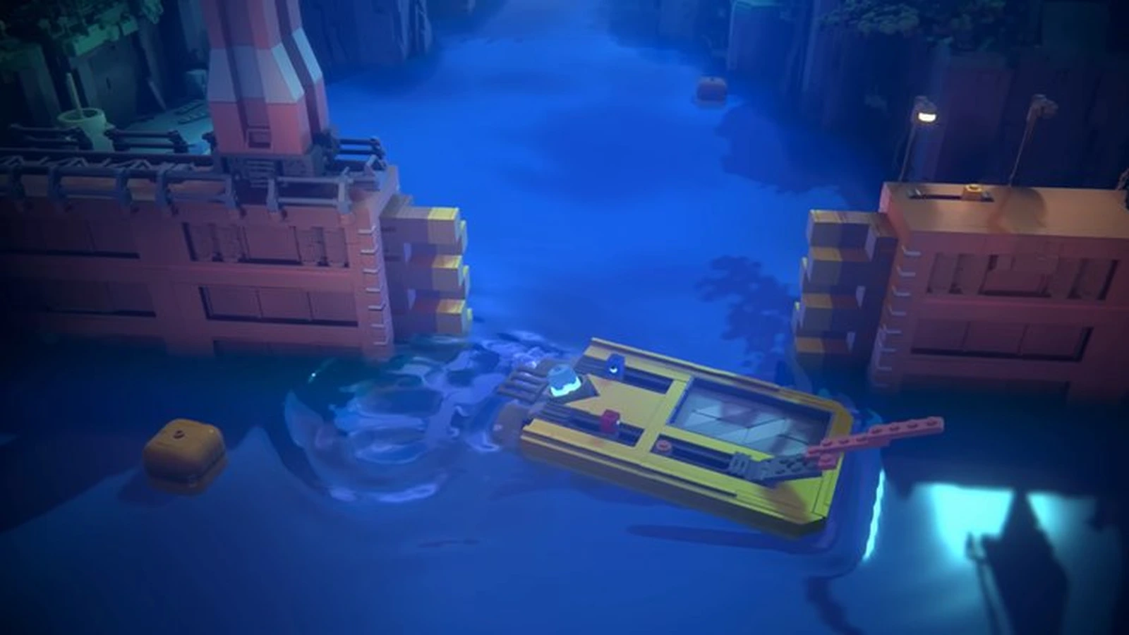 A yellow brick boat floats on deep blue water between two brick-built walls at night