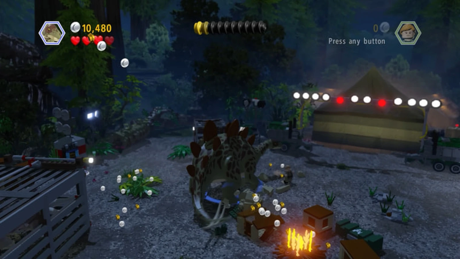 A LEGO stegosaurus smashes a campsite at night beside a campfire and a lit-up tent